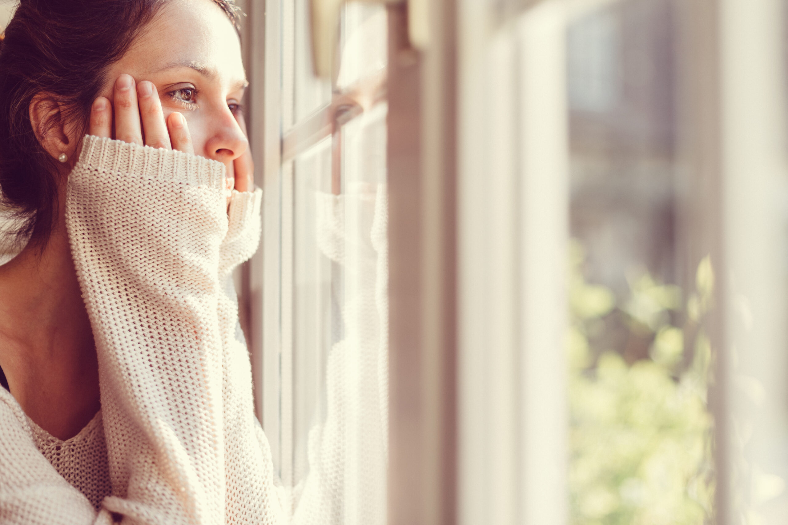 Sehnsuchtsvolle Frau am Fenster